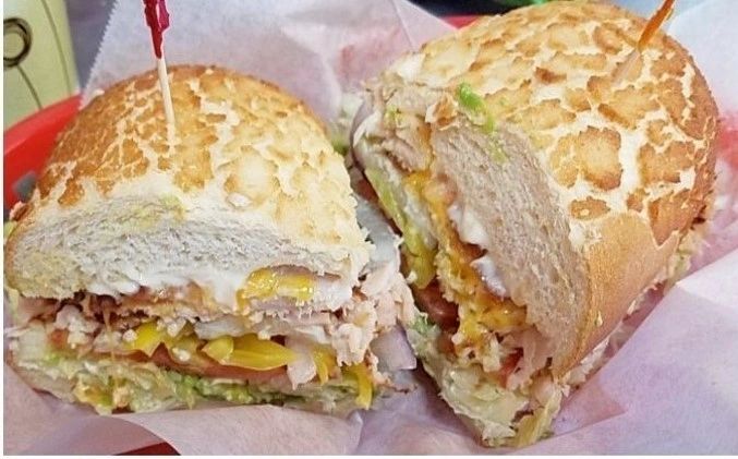 Golden Night sandwich with turkey, bacon, cheddar and avocado on a Dutch-crunch roll in a red basket