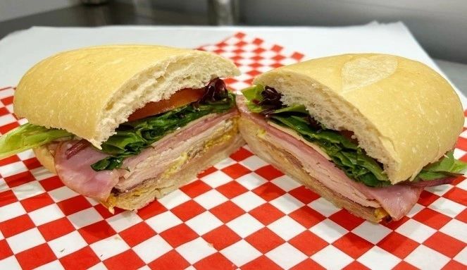 The 702 sandwich with turkey, ham and roast beef, cut in half on red-and-white checkered deli paper
